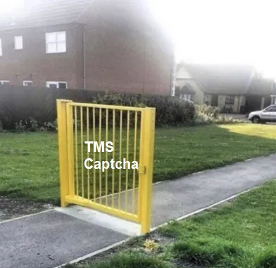 A yellow gate labelled “TMS Captcha” standing across a footpath, with open grass on both sides